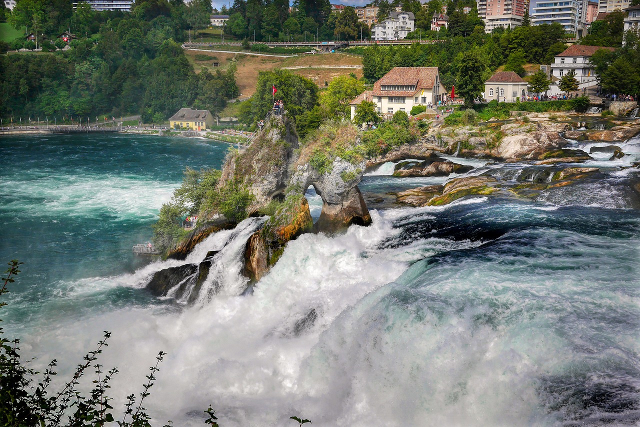 In this image, the visible elements include water, rocks, trees, buildings, poles, people, and the sky.\n
